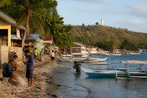 Apo Island shoreline with outrigger boats, village houses and lighthouse ridge
