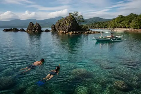 Snorkelers and a small boat near rocky islets off Baler’s coast
