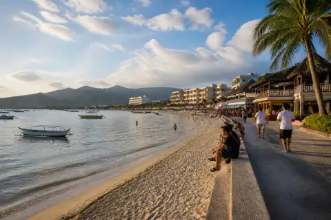 Resort-lined Baloy Long Beach shoreline with boats in Subic Bay at sunset