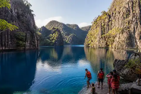 Barracuda Lake's steep limestone walls and deep blue water with visitors on a small landing