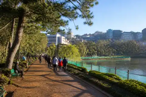 Morning view of Burnham Park with walking paths, pine trees and fenced Burnham Lake in Baguio