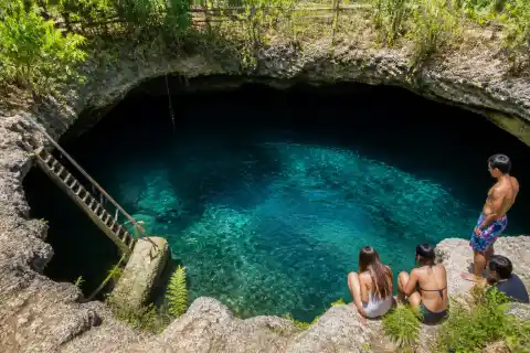 Collapsed limestone cave pool with ladder and blue-green water at Cabagnow, Anda, Bohol