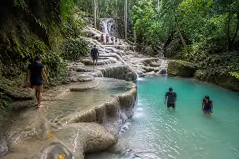 Visitors at Cambais Falls lower turquoise pool and limestone ledges in Alegria, Cebu