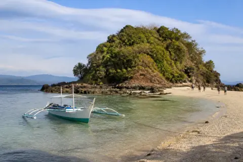 Colibra Island pale sand, rocky shoreline and a small banca at anchor