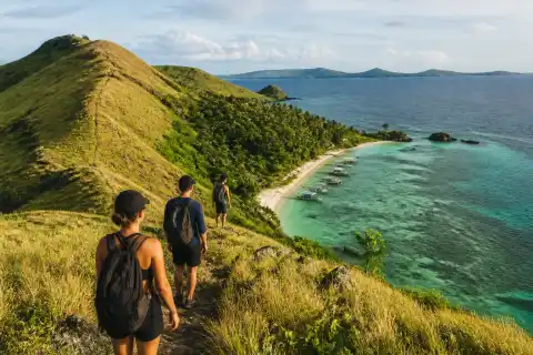 Hikers on Corregidor Island grassy ridge overlooking boats and shoreline
