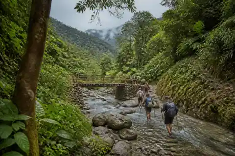 Hikers crossing the rocky river corridor toward Ditumabo Mother Falls in Aurora