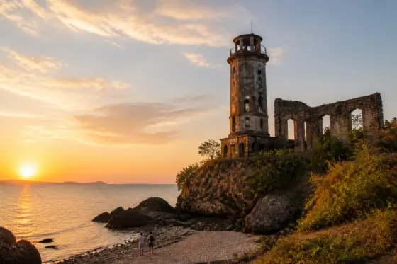 Guisi lighthouse ruins above a rocky coast at sunset, Guimaras