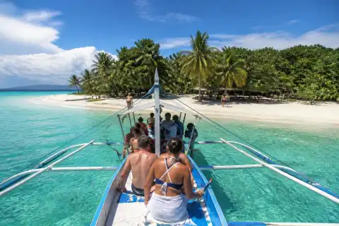 Outrigger boat approaching Cowrie Island beach at Honda Bay, Puerto Princesa