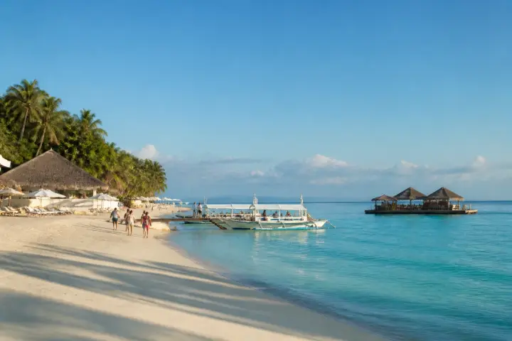 Lakawon Island pale-sand beach with cottages, landing boats and TawHai floating bar offshore
