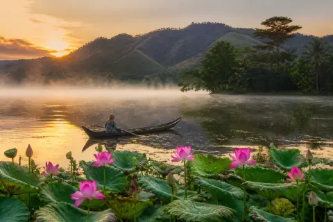 Sunrise over Lake Sebu with lotus flowers and a wooden boat
