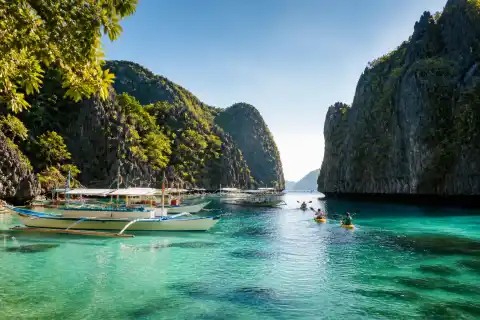 Limestone karsts and outrigger boats in a turquoise El Nido lagoon, Palawan