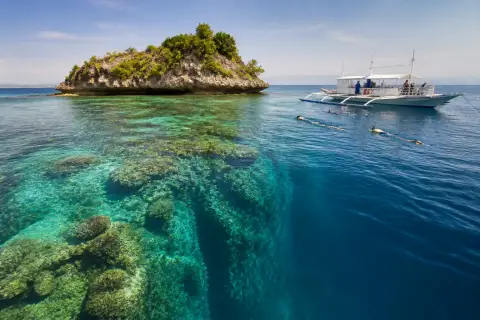 Boat and snorkelers near Pescador Island's reef wall off Moalboal