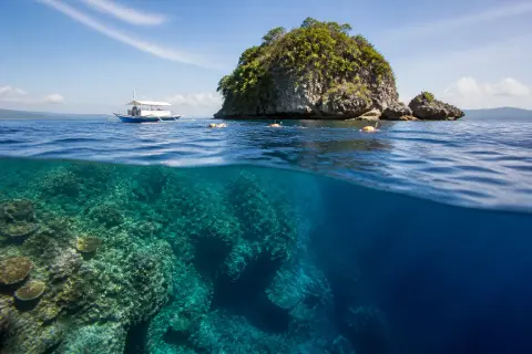 Snorkel boat and swimmers beside Pescador Island's reef wall
