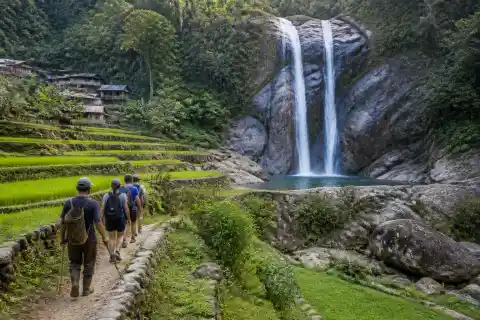 Twin cascade of Pongas Falls with rice terraces and hikers on the trail