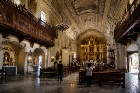 Interior nave of San Agustin Church showing painted ceiling and high retablo