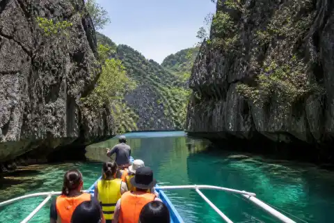 Outrigger boat entering a narrow limestone passage into a sheltered lagoon at Bucas Grande