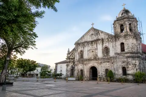 Coral‑stone facade of St. Peter the Apostle Parish and Bantayan town plaza with restoration barriers