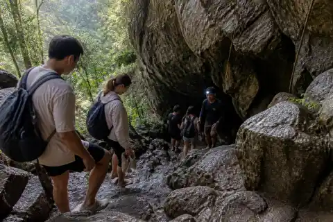 Visitors and a guide descending the rocky entrance of Sumaguing Cave in Sagada