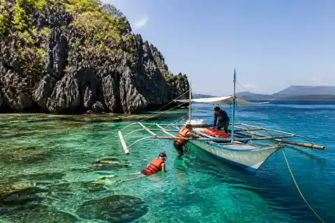 Banca and snorkelers beside a limestone island in Taytay Bay, Northern Palawan