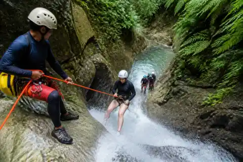 Guides and participants rappelling in a narrow Cebu canyon with a small waterfall