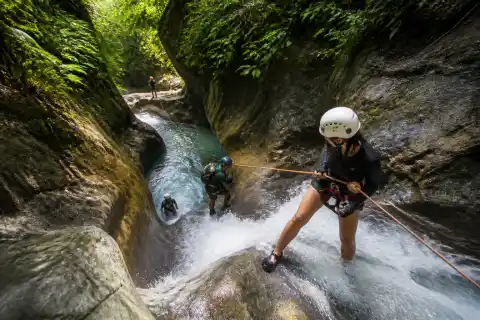 Guided canyoning group rappelling through a narrow tropical canyon in Cebu