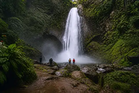 Tudaya Falls plunging into a rocky pool in forested Mt. Apo uplands with visitors at a safe distance