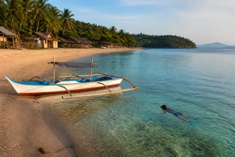 Mahabang Buhangin beach on Verde Island with a small local boat and palm trees