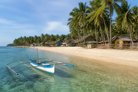Mahabang Buhangin beach at Verde Island with a small wooden boat and village in the background