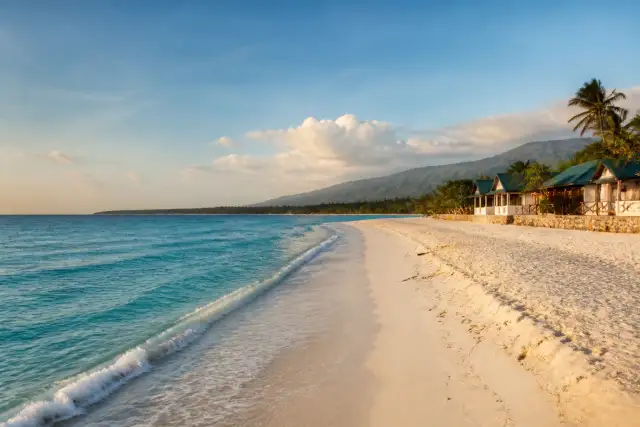 Saud Beach shoreline with white sand and gentle waves at sunrise