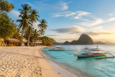 Turquoise Visayas beach with outrigger boats and limestone islet