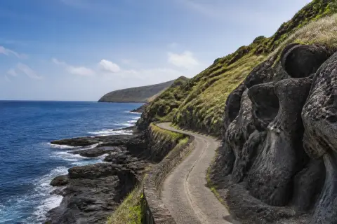 Dark wind-sculpted coastal rock and narrow road at Alapad, Batan Island