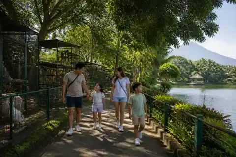 Family walking along a shaded lakeside path at Albay Park and Wildlife