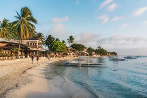 Alona Beach white-sand shoreline with boats and beachfront restaurants in morning light