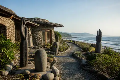 Pebble-and-stone house and outdoor sculpture garden at Bahay na Bato with Luna pebble shore beyond