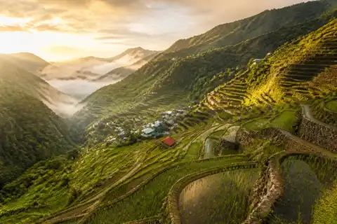 Layered rice terraces and village in Banaue, Ifugao, with valley mist