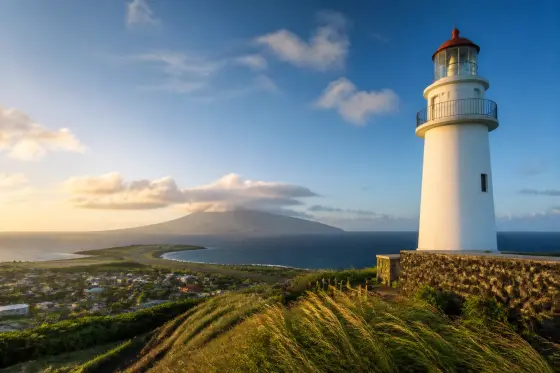 Basco Lighthouse on grassy Naidi Hills with Mount Iraya and the sea beyond