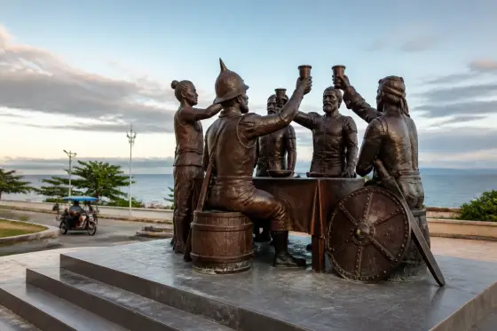 Bronze Blood Compact Monument on a seaside roadside platform with the Bohol Sea behind