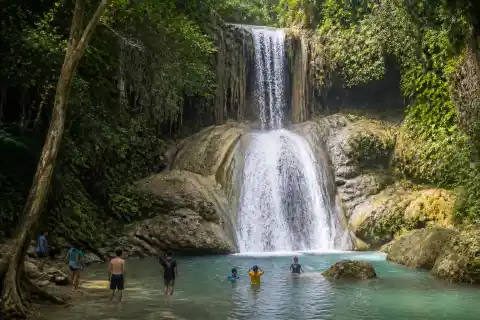 Two-level tropical waterfall with turquoise lower pool and surrounding jungle in Alegria, Cebu