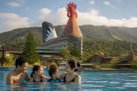 Family at a pool with Campuestohan’s rooster-shaped hotel visible in the background