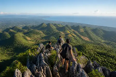 Hikers on Casino Peak's rocky ridge with Mantalongon hills and distant sea