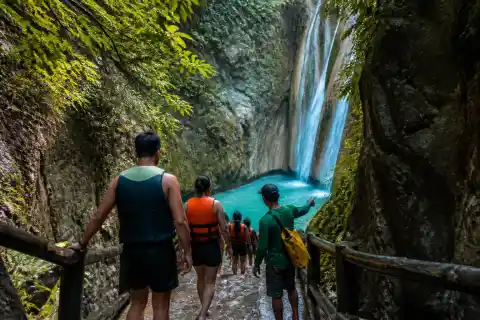 Travelers walking the narrow limestone canyon toward Dao Falls pool in Samboan