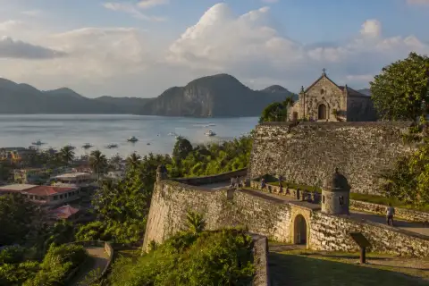 Fort Santa Isabel's restored coral-limestone walls overlooking Taytay Bay in late-afternoon light