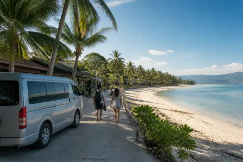Pale-sand Gumasa Beach with parked transfer van and two travelers
