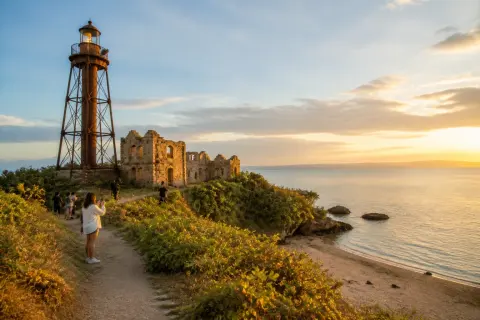 Rusted Guisi Lighthouse and stone ruins on a coastal headland above Guisi Beach, Guimaras