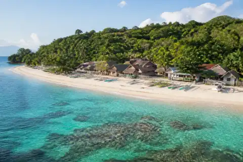 White‑sand beach with fishing boats and shoreline village at Himokilan Island, Cuatro Islas, Leyte