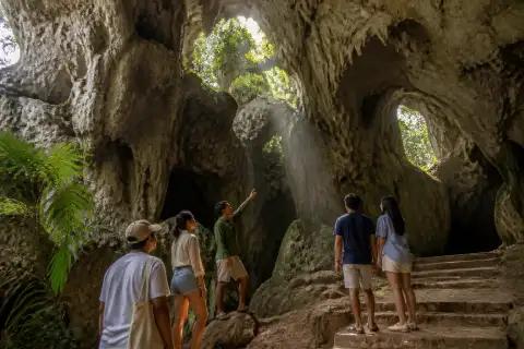 Visitors and a guide at the limestone entrance and steps of Hoyop-Hoyopan Cave in Camalig