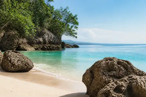 Pale-sand cove with large coral-rock boulders at Kagusuan Beach, Maria, Siquijor