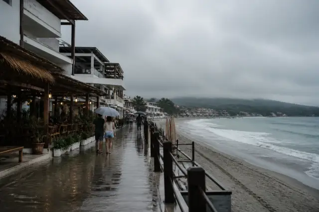 Overcast Urbiztondo surf strip with cafés and wet pavement