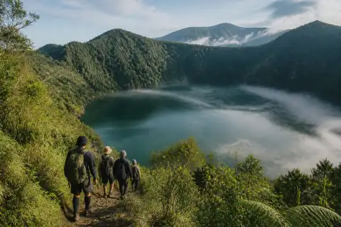 Crater lake with forested slopes and trekkers approaching (Lake Holon historical view)