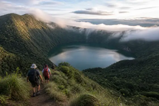 Hikers on a ridge overlooking Lake Holon’s forested crater lake